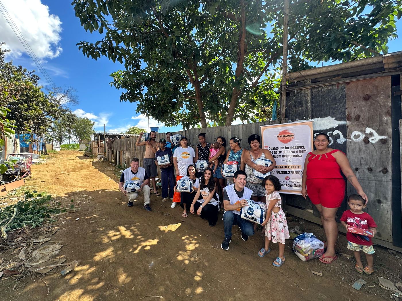 Voluntários e moradores com cestas básicas em rua de terra