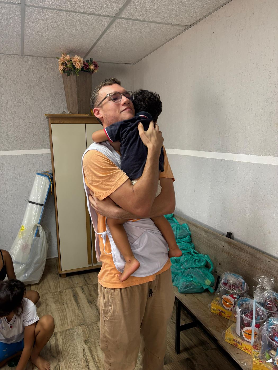 Voluntário abraçando uma criança durante a visita