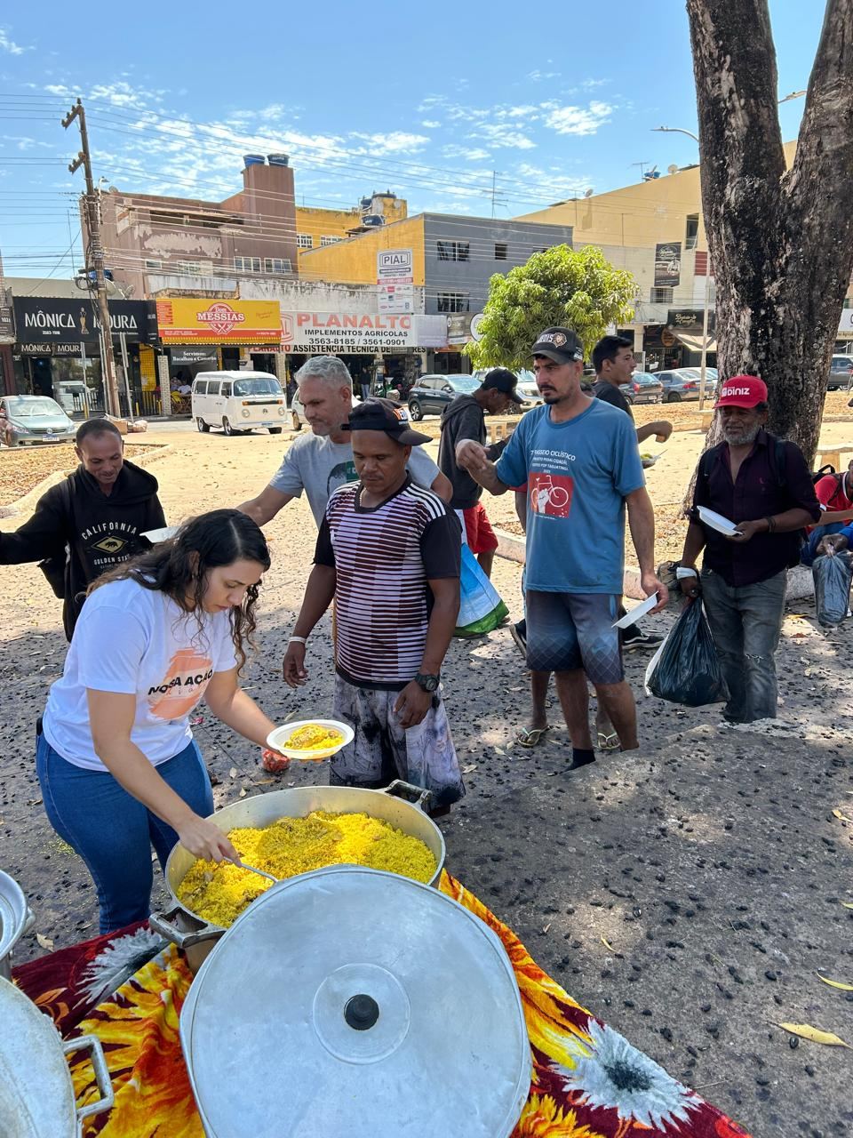 Voluntária servindo comida quente para pessoas em situação de rua