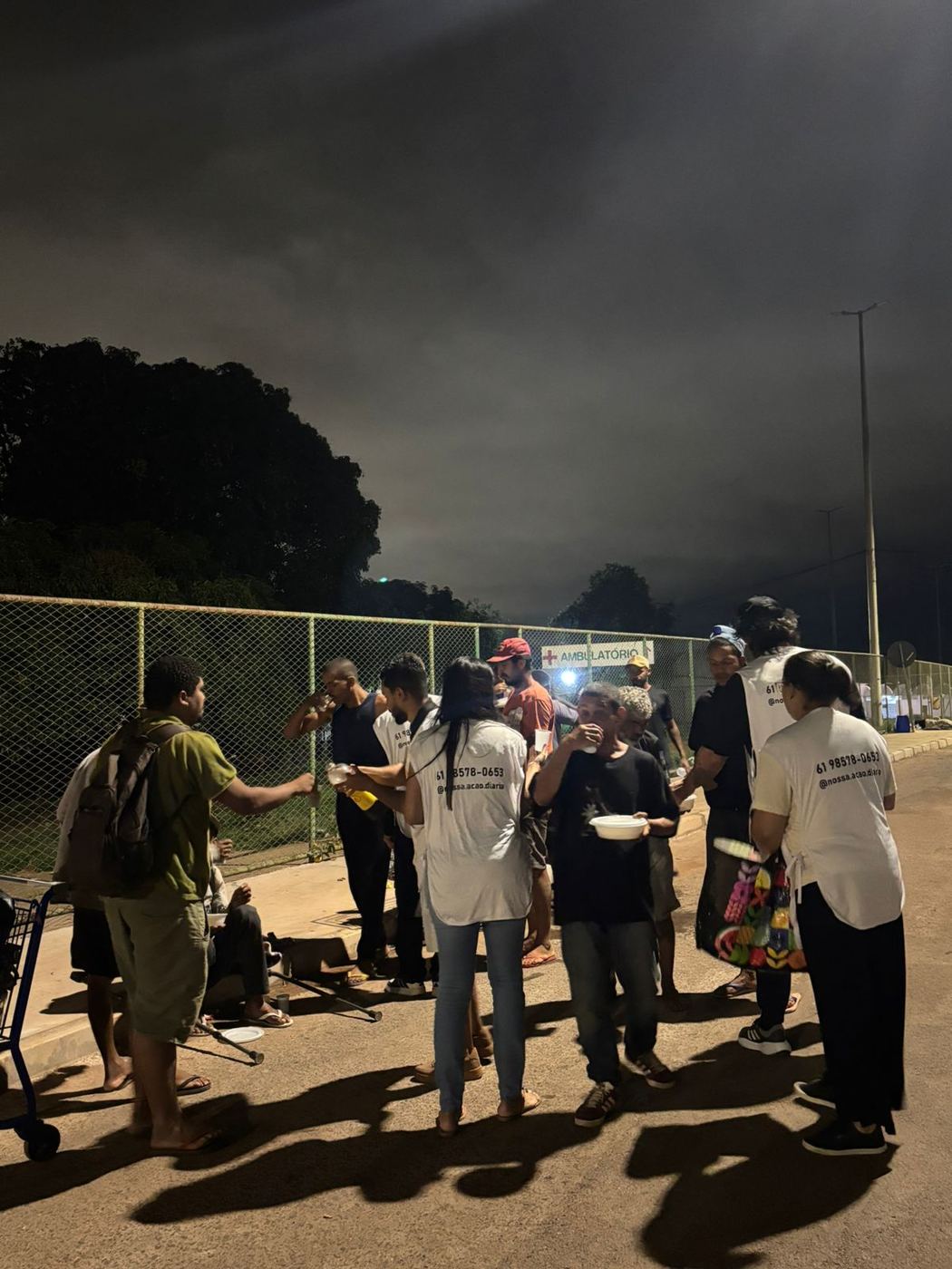 Grupo de voluntários servindo comida na beira da pista à noite